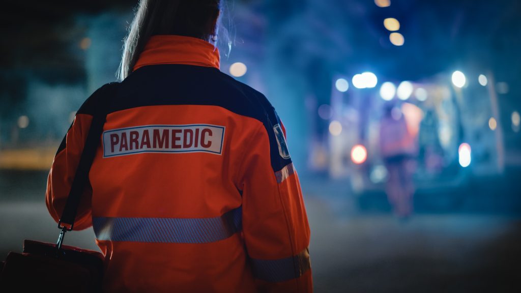 Uniformed paramedic standing with her back to the camera​