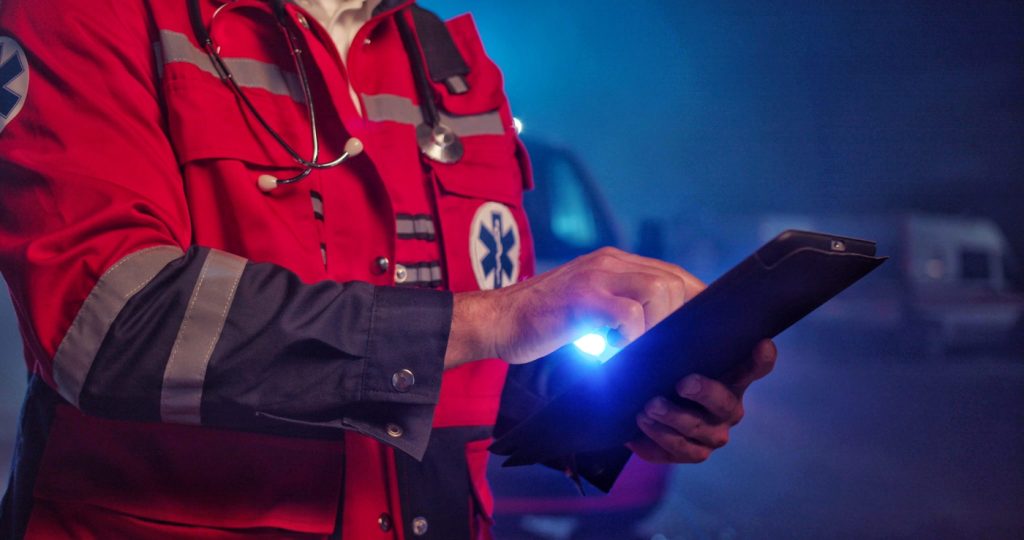 Paramedic in a coat working on a tablet computer