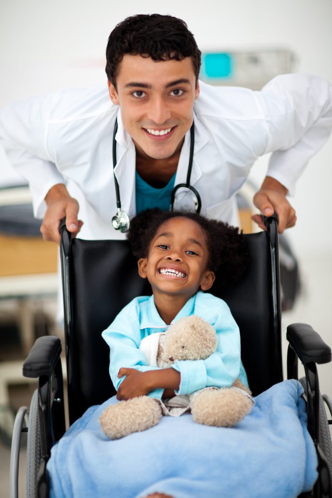 Young child in wheelchair being cared for by a doctor