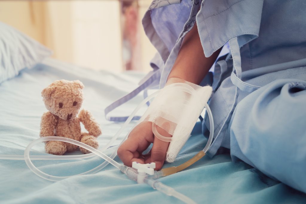 Child who has fever sitting with teddy bear in hospital